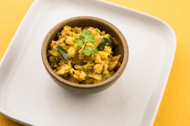 patates kuru ve baharatlı reciepy da aalu sabji veya aalu bhaji olarak bilinen, roti / chapati / paratha / dosa / naan ile servis, beyaz plaka kahverengi rustik kase servis, sarı arka plan üzerinde izole