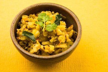 patates kuru ve baharatlı reciepy da aalu sabji veya aalu bhaji olarak bilinen, roti / chapati / paratha / dosa / naan ile servis, beyaz plaka kahverengi rustik kase servis, sarı arka plan üzerinde izole
