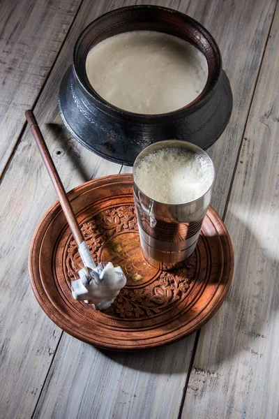 Indian sweet Lassi made up of milk, curd, sugar and salt mixed with ice cubes, served in a jumbo steel glass, prepared in traditional earthen pot — Stock Photo, Image