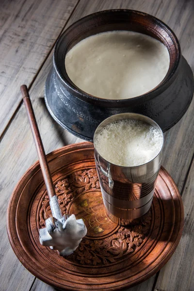 Indian sweet Lassi made up of milk, curd, sugar and salt mixed with ice cubes, served in a jumbo steel glass, prepared in traditional earthen pot — Stock Photo, Image