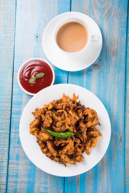 Çıtır soğan bhaji veya kanda bhaji veya kızarmış soğan pakore veya pakode, lezzetli sokak gıda, favori Hint aperatif muson içinde sıcak çay ile servis