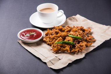 Çıtır soğan bhaji veya kanda bhaji veya kızarmış soğan pakore veya pakode, lezzetli sokak gıda, favori Hint aperatif muson içinde sıcak çay ile servis
