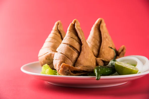 Comida india famosa merienda Samosa en un plato con limón, cebolla y chile frito verde —  Fotos de Stock