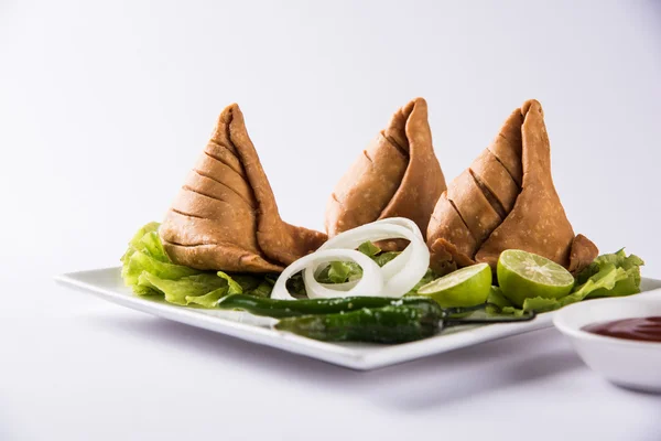 Ινδικό διάσημο σνακ φαγητό samosa σε ένα πιάτο με λεμόνι, κρεμμύδι και πράσινο τηγανητό τσίλι — Φωτογραφία Αρχείου