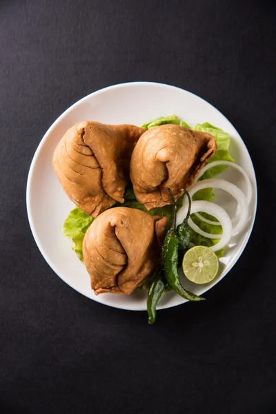 Indian famous snack food Samosa on a plate with lemon, onion and green fried chilli — Stock Photo, Image