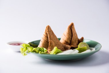 limon, soğan ve yeşil kızarmış biber ile bir tabak üzerinde hint ünlü snack gıda Samosa