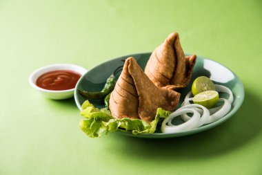 limon, soğan ve yeşil kızarmış biber ile bir tabak üzerinde hint ünlü snack gıda Samosa