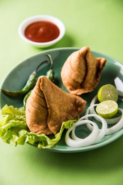 limon, soğan ve yeşil kızarmış biber ile bir tabak üzerinde hint ünlü snack gıda Samosa