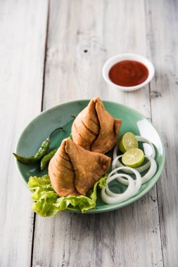 limon, soğan ve yeşil kızarmış biber ile bir tabak üzerinde hint ünlü snack gıda Samosa