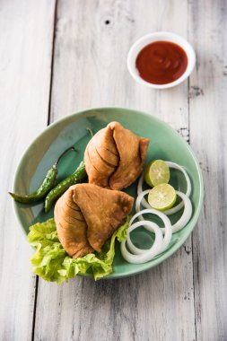 limon, soğan ve yeşil kızarmış biber ile bir tabak üzerinde hint ünlü snack gıda Samosa