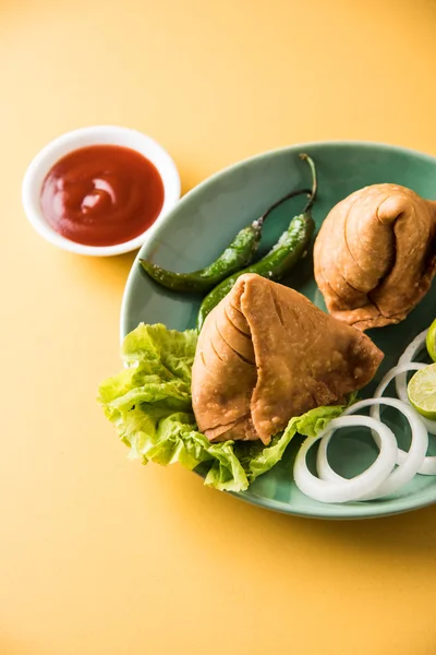 Comida de refeição leve famosa indiana Samosa em um prato com limão, cebola e pimenta frita verde — Fotografia de Stock