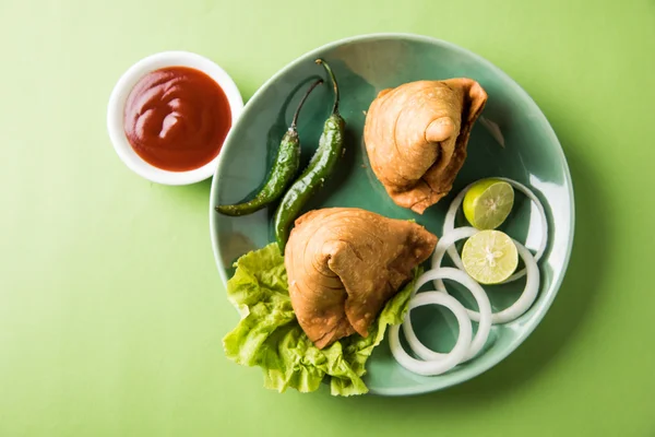 Cibo indiano famoso spuntino Samosa su un piatto con limone, cipolla e peperoncino fritto verde — Foto Stock