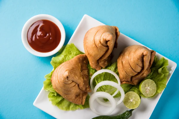 Comida india famosa merienda Samosa en un plato con limón, cebolla y chile frito verde —  Fotos de Stock