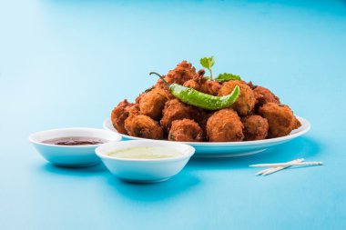 Lezzetli lezzetli ve nefis Hint Moong Dal vada veya moong dal pakoda veya moong vada veya moong vade veya Pakora (börek) ile kızarmış yeşil biber, kırmızı ve yeşil acı sos.