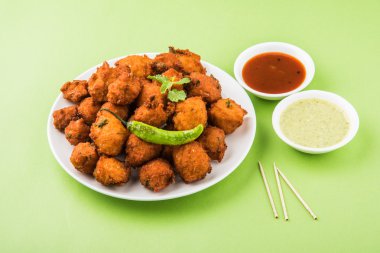 Lezzetli lezzetli ve nefis Hint Moong Dal vada veya moong dal pakoda veya moong vada veya moong vade veya Pakora (börek) ile kızarmış yeşil biber, kırmızı ve yeşil acı sos.