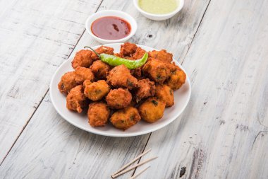 Lezzetli Lezzetli ve Nefis Hint Moong Dal vada veya moong dal pakoda veya moong vada veya moong vade veya Pakora veya pakode (Fritter) kızarmış yeşil biber, kırmızı ve yeşil sıcak sos ile.