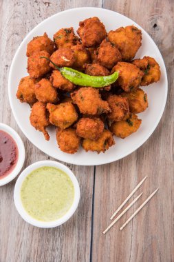 Lezzetli Lezzetli ve Nefis Hint Moong Dal vada veya moong dal pakoda veya moong vada veya moong vade veya Pakora veya pakode (Fritter) kızarmış yeşil biber, kırmızı ve yeşil sıcak sos ile.