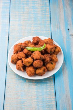 Lezzetli Lezzetli ve Nefis Hint Moong Dal vada veya moong dal pakoda veya moong vada veya moong vade veya Pakora veya pakode (Fritter) kızarmış yeşil biber, kırmızı ve yeşil sıcak sos ile.