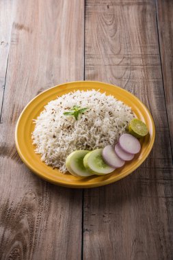 Jeera pirinç, uzun taneli basmati kızarmış Kimyon tohumu, sarı bir seramik tabak içinde yeşil salata ile servis ile aromalı pirinç pişmiş