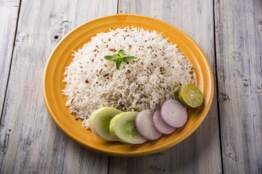 Jeera pirinç, uzun taneli basmati kızarmış Kimyon tohumu, sarı bir seramik tabak içinde yeşil salata ile servis ile aromalı pirinç pişmiş