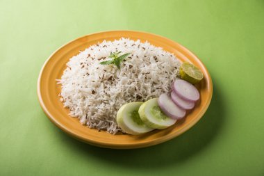 Jeera pirinç, uzun taneli basmati kızarmış Kimyon tohumu, sarı bir seramik tabak içinde yeşil salata ile servis ile aromalı pirinç pişmiş