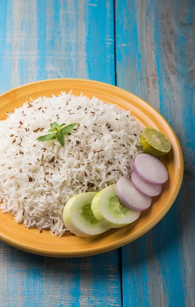 Arroz jeera, arroz basmati cozido de grão longo aromatizado com sementes de cominho frito, servido em uma placa cerâmica amarela com salada verde — Fotografia de Stock