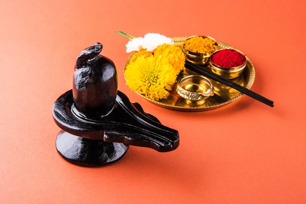 Shiva Linga opgebouwd uit zwarte steen, versierd met bloemen & bael blad bekend als Aegle marmelos, op zwarte achtergrond, maha shiva ratri een festival van Hindoe God shankar shankar bhagwan of bholenath — Stockfoto