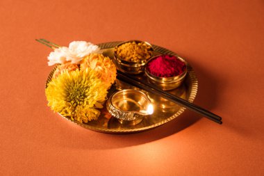 Güzel dekore edilmiş Pooja Thali için diwali celebration ibadet, huldi veya zerdeçal tozu ve Recep, çiçekler, kokulu pirinç levha turuncu arka plan, hindu puja thali üzerinde sopa