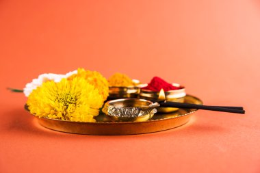 Güzel dekore edilmiş Pooja Thali için diwali celebration ibadet, huldi veya zerdeçal tozu ve Recep, çiçekler, kokulu pirinç levha turuncu arka plan, hindu puja thali üzerinde sopa