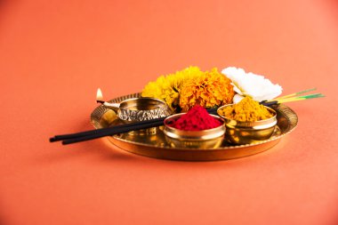 Güzel dekore edilmiş Pooja Thali için diwali celebration ibadet, huldi veya zerdeçal tozu ve Recep, çiçekler, kokulu pirinç levha turuncu arka plan, hindu puja thali üzerinde sopa