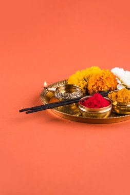 Güzel dekore edilmiş Pooja Thali için diwali celebration ibadet, huldi veya zerdeçal tozu ve Recep, çiçekler, kokulu pirinç levha turuncu arka plan, hindu puja thali üzerinde sopa