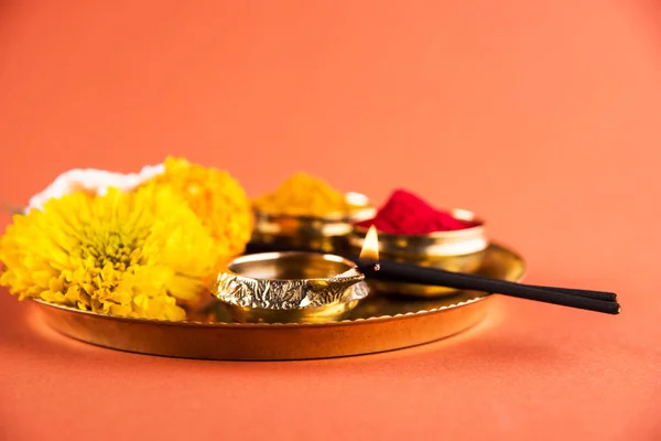 Bellamente decorado Pooja Thali para la celebración diwali para adorar, huldi o cúrcuma en polvo y kumkum, flores, palos perfumados en placa de latón sobre fondo naranja, hindú puja thali —  Fotos de Stock