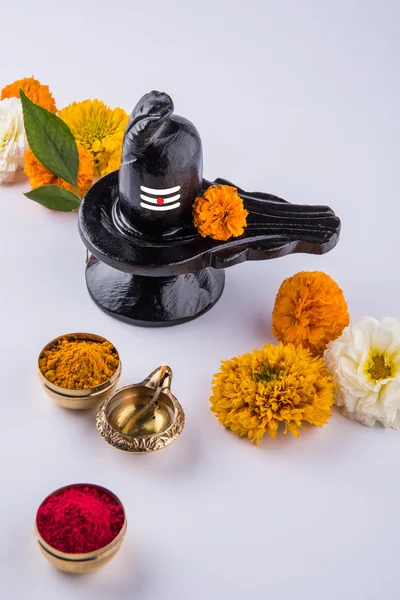 Shiva Linga compuesta de piedra negra decorada con flores y hoja de bael conocida como Aegle marmelos, sobre fondo negro, maha shiva ratri un festival de Dios hindú shankar o shankar bhagwan o bholenath —  Fotos de Stock