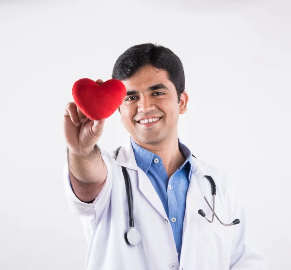 Handsome indian doctor holding heart stuffed toy, doctor with red heart, asian doctor and heart care concept, isolated on white background, heart in hands of doctor — Stock Photo, Image