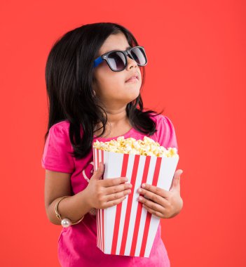 mutlu kız patlamış mısır yeme ve gözlük takan, hint kız patlamış mısır, asyalı kız ve patlamış mısır, kırmızı arka plan üzerinde patlamış mısır yeme hint kız