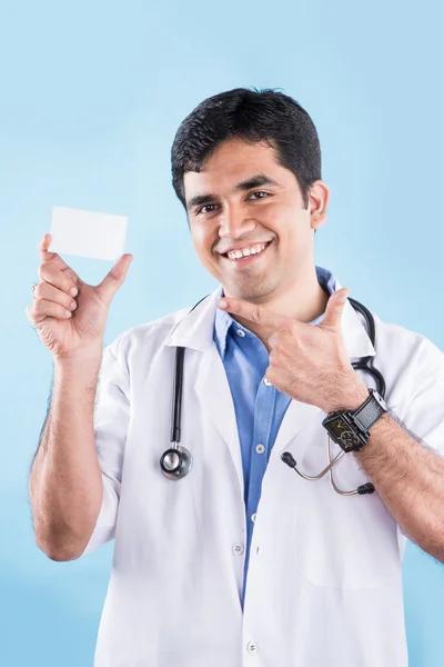 Closeup portrait of confident indian healthcare professional or doctor or nurse with stethoscope, holding up business card, copy space, indian male doctor with blank card, isolated on blue background — Stock Photo, Image