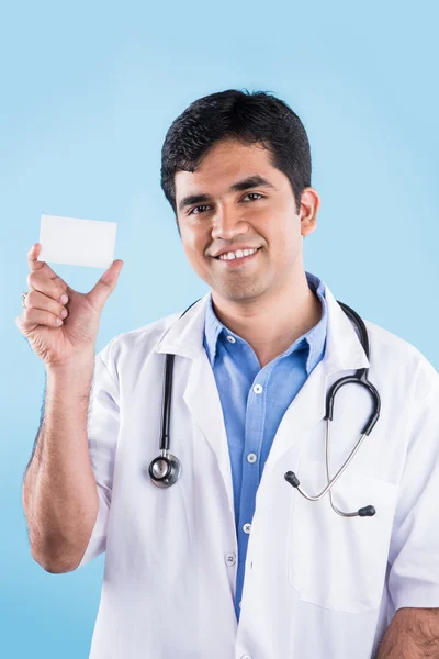 Closeup portré magabiztos indiai egészségügyi szakember vagy orvos vagy a nővér sztetoszkóppal, feltartotta névjegykártya, másolás tér, Indiai férfi orvos, üres kártya, elszigetelt kék háttér — Stock Fotó