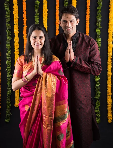 indian young couple praying in traditional cloths, indian newly married couple in namaskar or welcoming pose or prayer pose