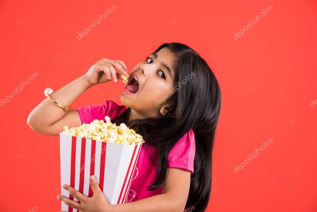 Happy girl eating popcorn and wearing glasses, indian girl eating