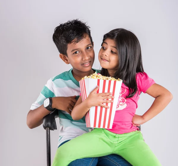 different moods while small indian girl child and boy eating popcorn