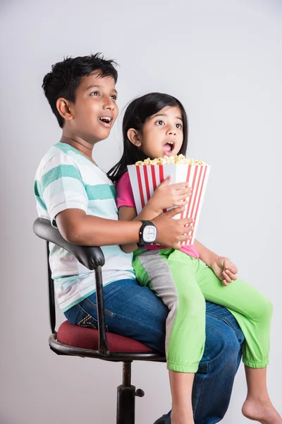 different moods while small indian girl child and boy eating popcorn