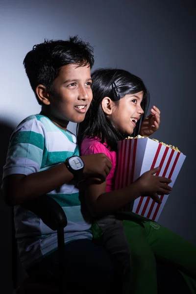 Different moods while small indian girl child and boy eating popcorn — Stock Photo, Image