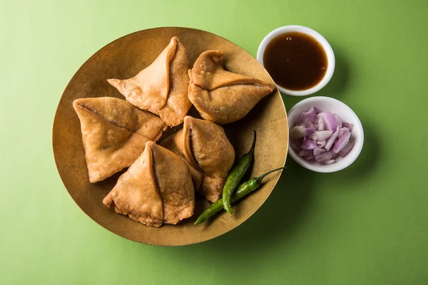 Vegetarian Aloo samosa or samosas. Indian special traditional street food.  Famous Indian Punjabi samosa filled with spicy boiled potato mixture.  served with green and red chutneys. Copy space. Stock Photo