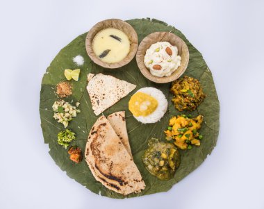 typical maharashtrian food served in plate and bowls made of leaf includes kadhi and shrikhand, plain dal, spinach curry, aalu mutter, plain rice, papad, bhakri or bhakar or roti and variety of salad clipart