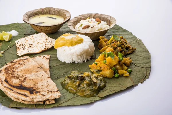 Typical maharashtrian food served in plate and bowls made of leaf includes kadhi and shrikhand, plain dal, spinach curry, aalu mutter, plain rice, papad, bhakri or bhakar or roti and variety of salad — Stock Photo, Image