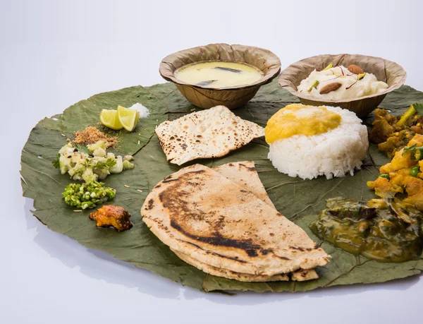 Comida típica maharashtriana servida em prato e tigelas feitas de folha inclui kadhi e shrikhand, dal liso, caril de espinafre, murmúrio aalu, arroz liso, papad, bhakri ou bhakar ou roti e variedade de salada — Fotografia de Stock