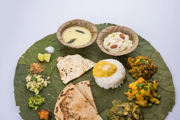 Typical maharashtrian food served in plate and bowls made of leaf includes kadhi and shrikhand, plain dal, spinach curry, aalu mutter, plain rice, papad, bhakri or bhakar or roti and variety of salad — Stock Photo, Image