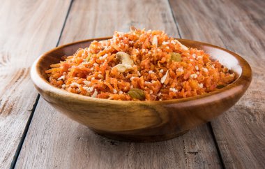 tasty gajar halwa or gajar ka halwa made up or fresh carrot, sugar and milk. decorated with almond or badam, cashewnuts and pistachios, favourite north indian dessert usually served in weddings clipart