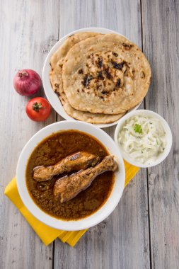 The most popular reddish chicken curry in the UK, india, pakistan, asia, chicken tikka masala, here served in bowl, accompanied by pilau rice and chapatis clipart
