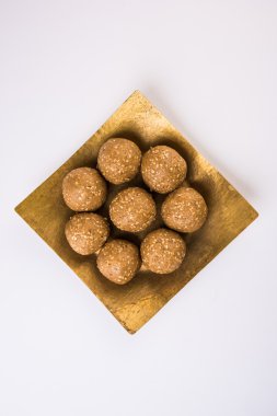Hint susam tatlı veya tilgul laddu, jaggery ve susam oluşan, Makar Sankranti festivali için hint tatlı, jaggery & çiğ susam ile terracotta kase